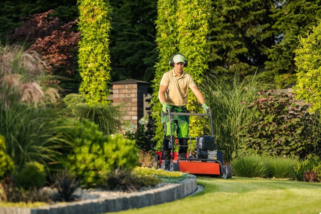 A man mows the lawn with a mower, carefully cutting the grass in a neat and tidy garden setting.